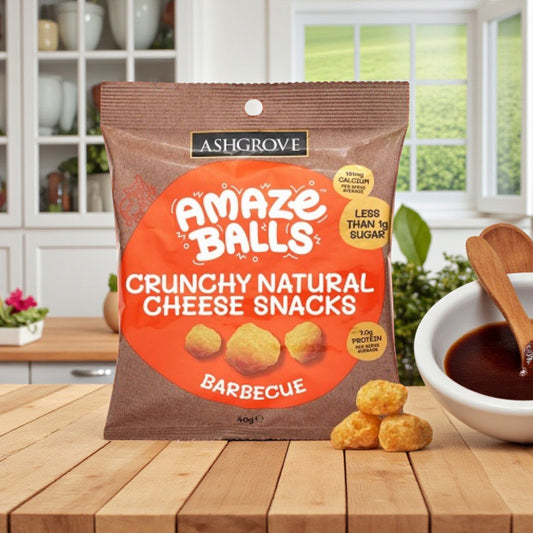 Packaging of Ashgrove Cheese AmazeBalls Crunchy Natural Cheese Snacks on a wooden table with a kitchen background.