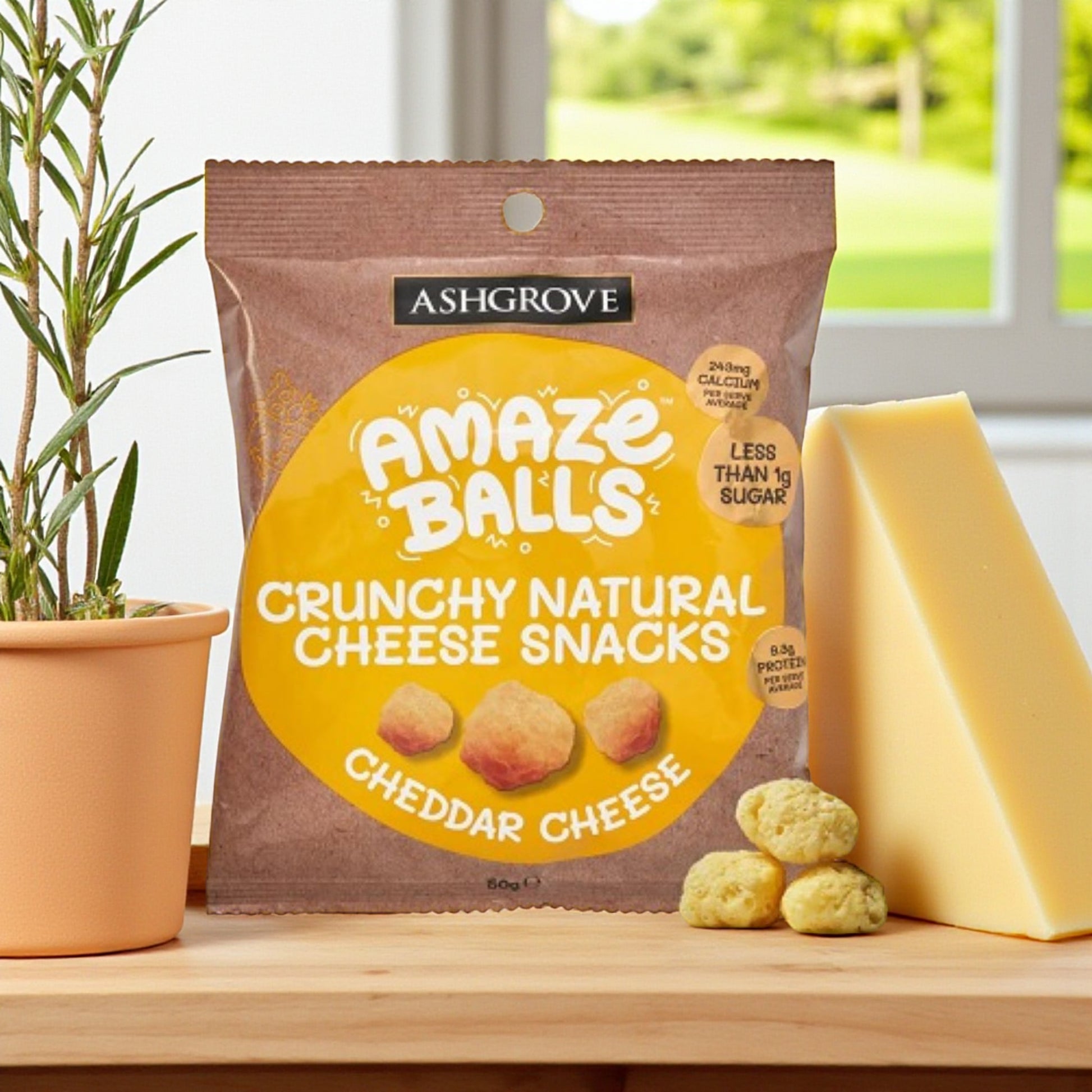 Packaging of Ashgrove Cheese AmazeBalls crunchy natural cheese snacks on a wooden surface with cheddar cheese.