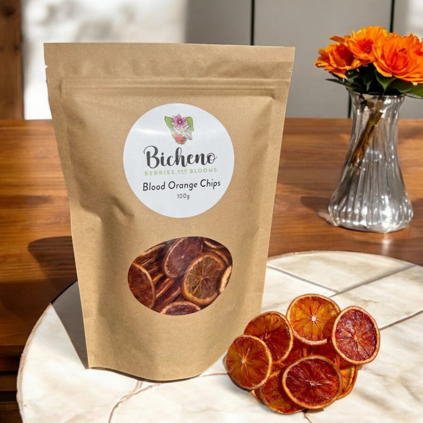 A package of Bicheno Tasmania blood orange chips. The product is next to a vase of orange flowers.