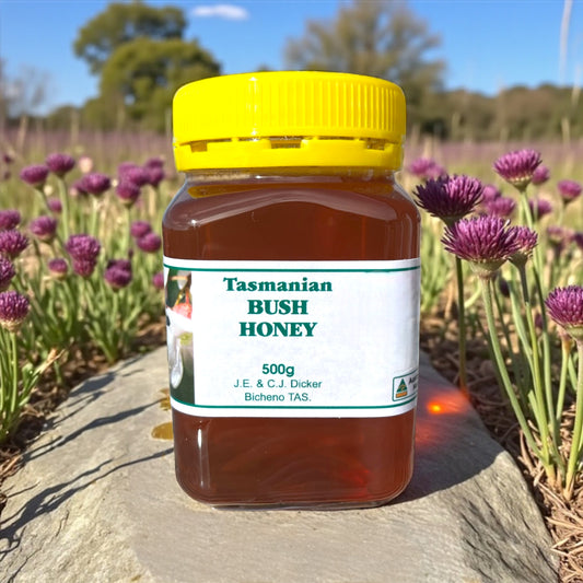 Jar of Tasmanian Bush Honey with a yellow lid on a rock with flowers in the background