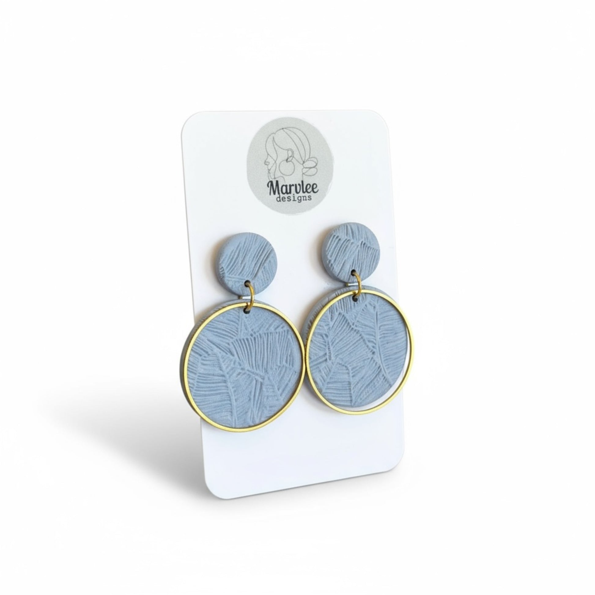 Close-up of Andy earrings showing botanical leaf impressions in blue-grey polymer clay with gold hoop frame