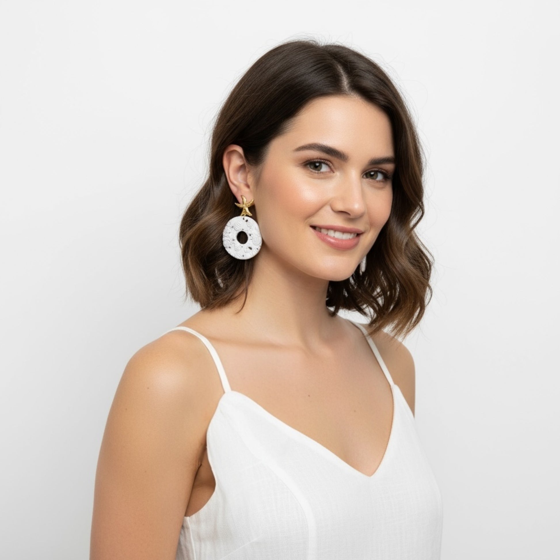 Woman wearing Aspley large beach wedding statement dangle earrings showing gold starfish and white seashell details by MarvLee Designs Tasmania