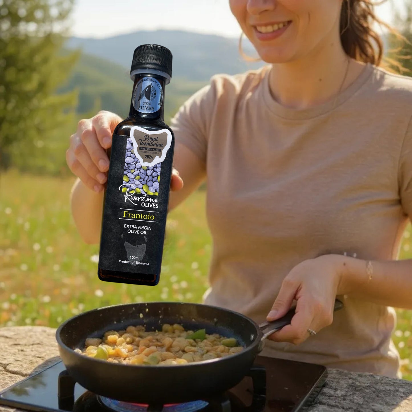 Person cooking outdoors with a bottle of Riverstone Extra Virgin Olive Oil Tasmania