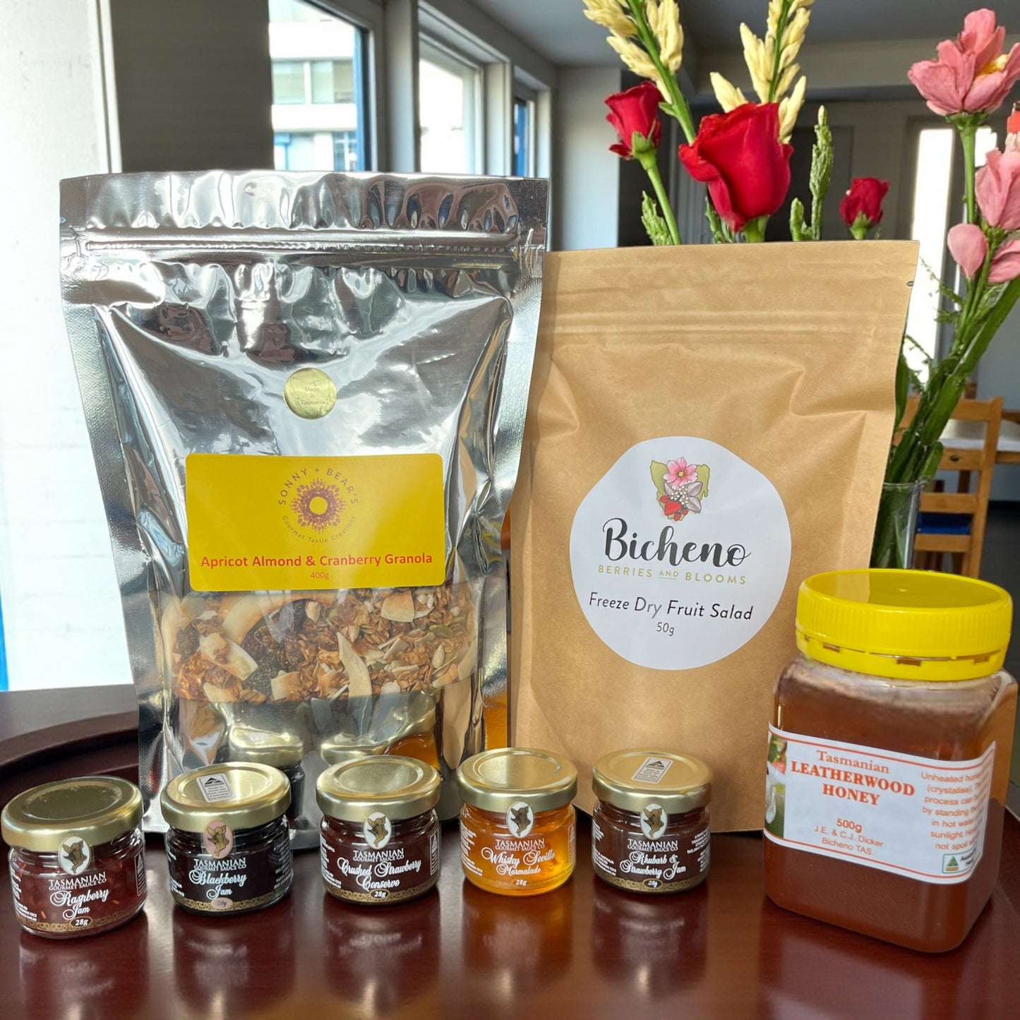 Assorted Tasmanian breakfast food products including a bag of freeze dried fruit salad, local honey, goumet jams and granola on a table.