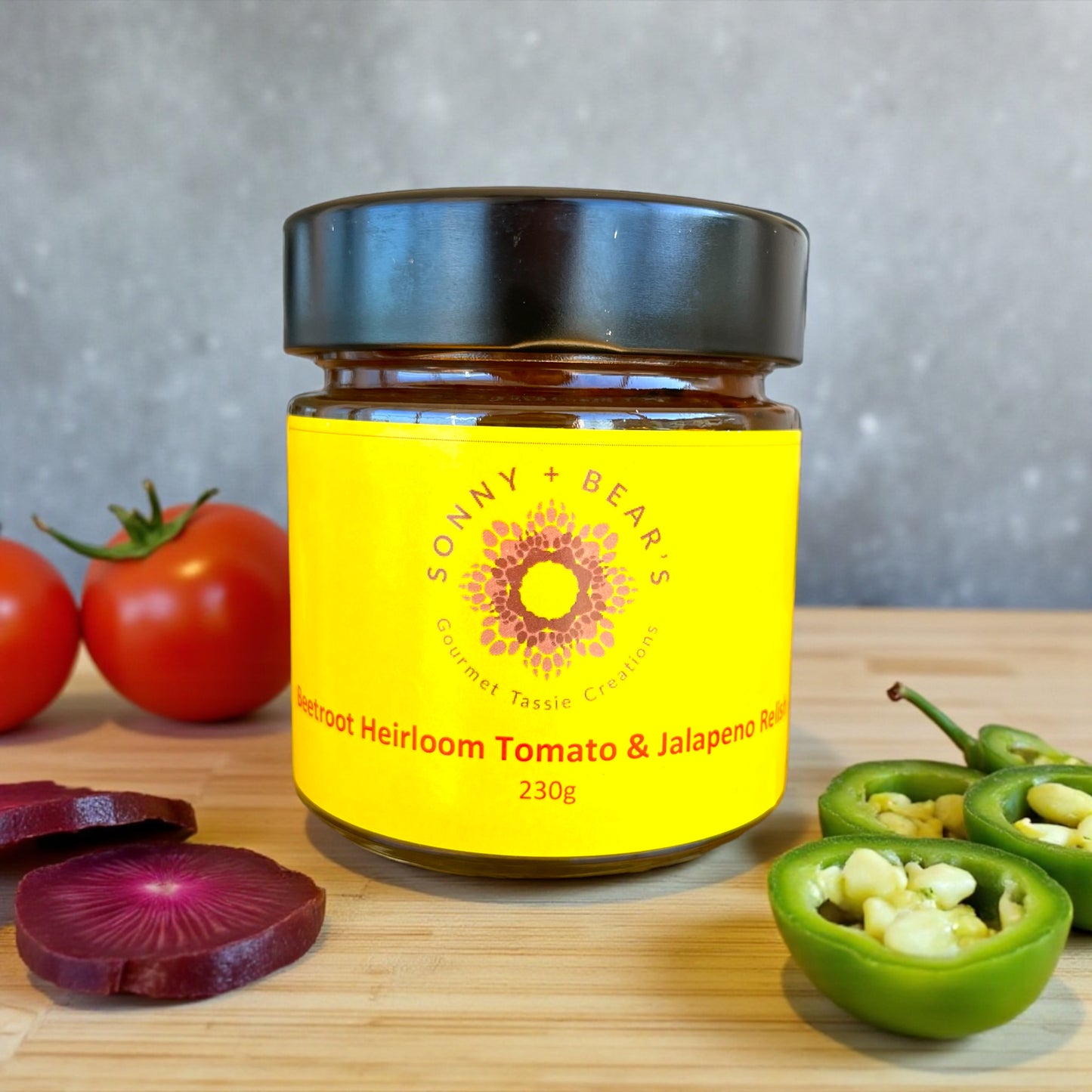 Jar of Sonny Bear's Tasmanian gourmet relish on a wooden board with heirloom tomatoes and jalapeños.