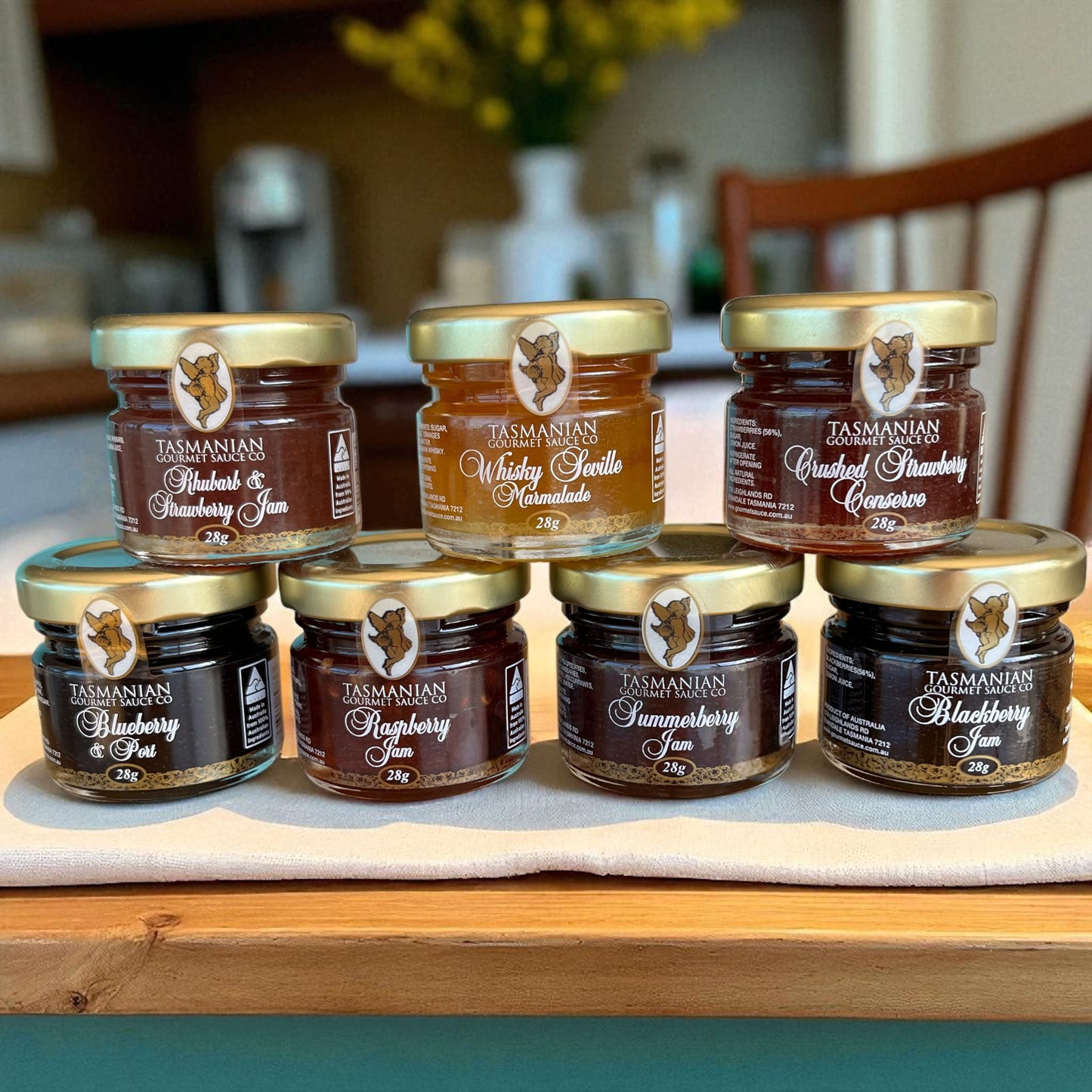 Seven pack of assorted jars of Tasmanian preserves on a kitchen counter.