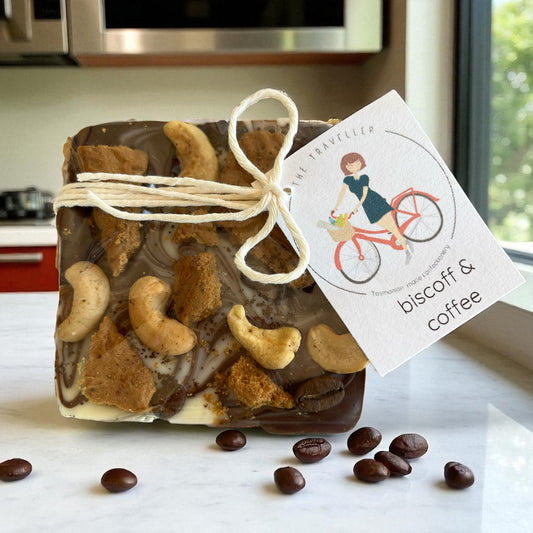 Bar of Tasmanian chocolate with cookie crumbles, cashews and coffee beans on a kitchen counter.