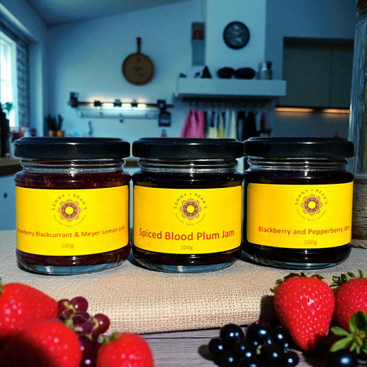 Three jars of unique Tasmanian jams with yellow labels on a kitchen counter with fruits in the foreground.