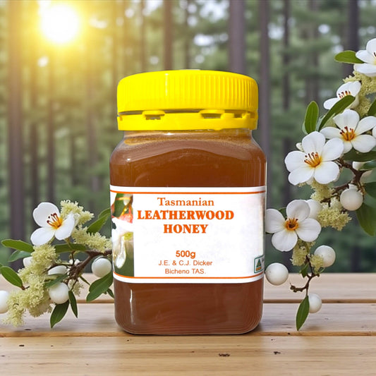Jar of Tasmanian Leatherwood Honey with a yellow lid on a wooden surface with leatherwood flowers in the background