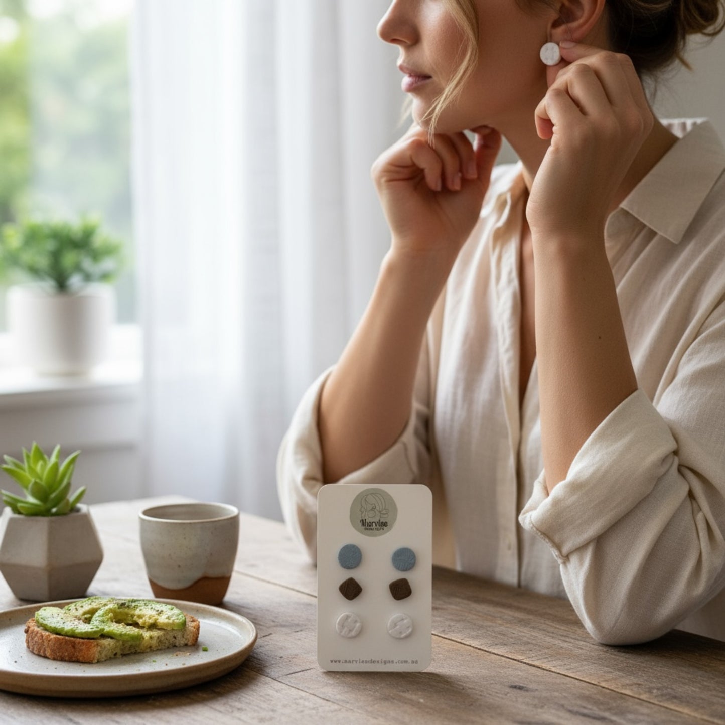 Woman sitting at a table with small handmade Tasmanian polymer clay stud earrings