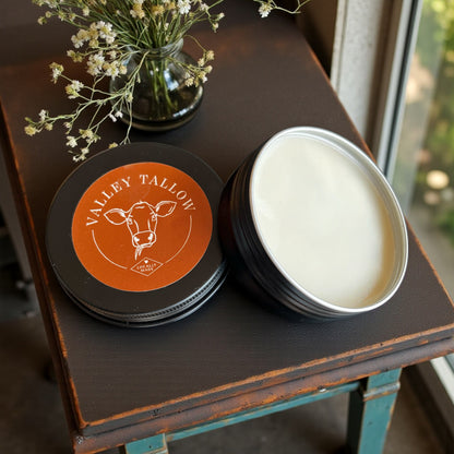 Tasmanian Valley Tallow Lavender Vanilla Hand and Body Balm tins with orange label displayed on vintage furniture with dried flowers