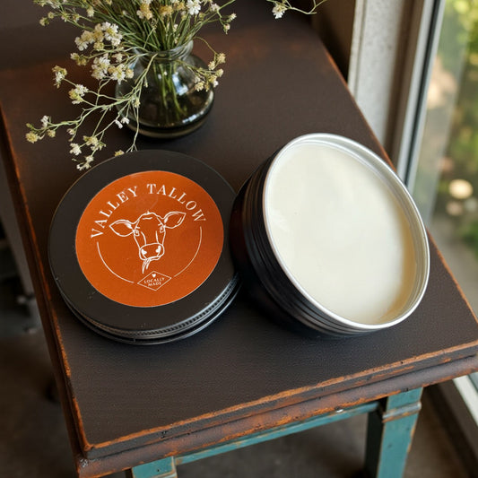 Tasmanian Valley Tallow Lavender Vanilla Hand and Body Balm tins with orange label displayed on vintage furniture with dried flowers