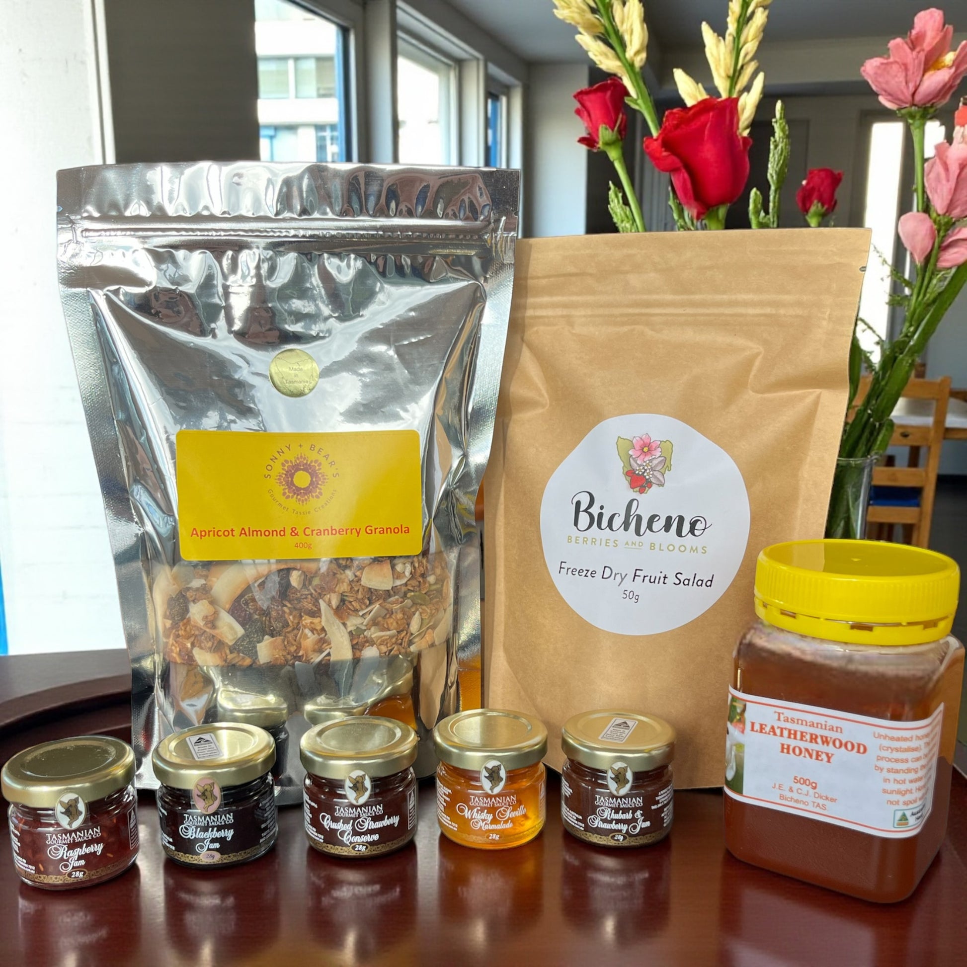 Assorted Tasmanian breakfast food products including a bag of freeze dried fruit salad, local honey, goumet jams and granola on a table.