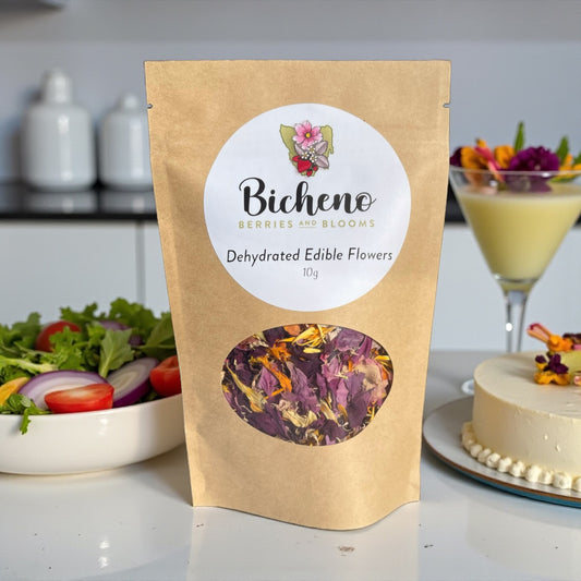 Bag of Bicheno Berries and Blooms Tasmania dehydrated mixed edible flowers on a kitchen counter with a cake, cocktail and salad in the background.