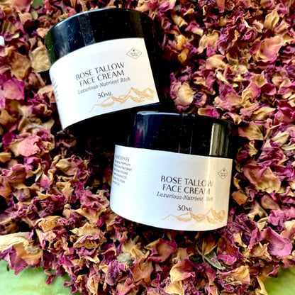 Two jars of Tassie Tallow Rose Tallow Face Cream on a bed of dried red roses.