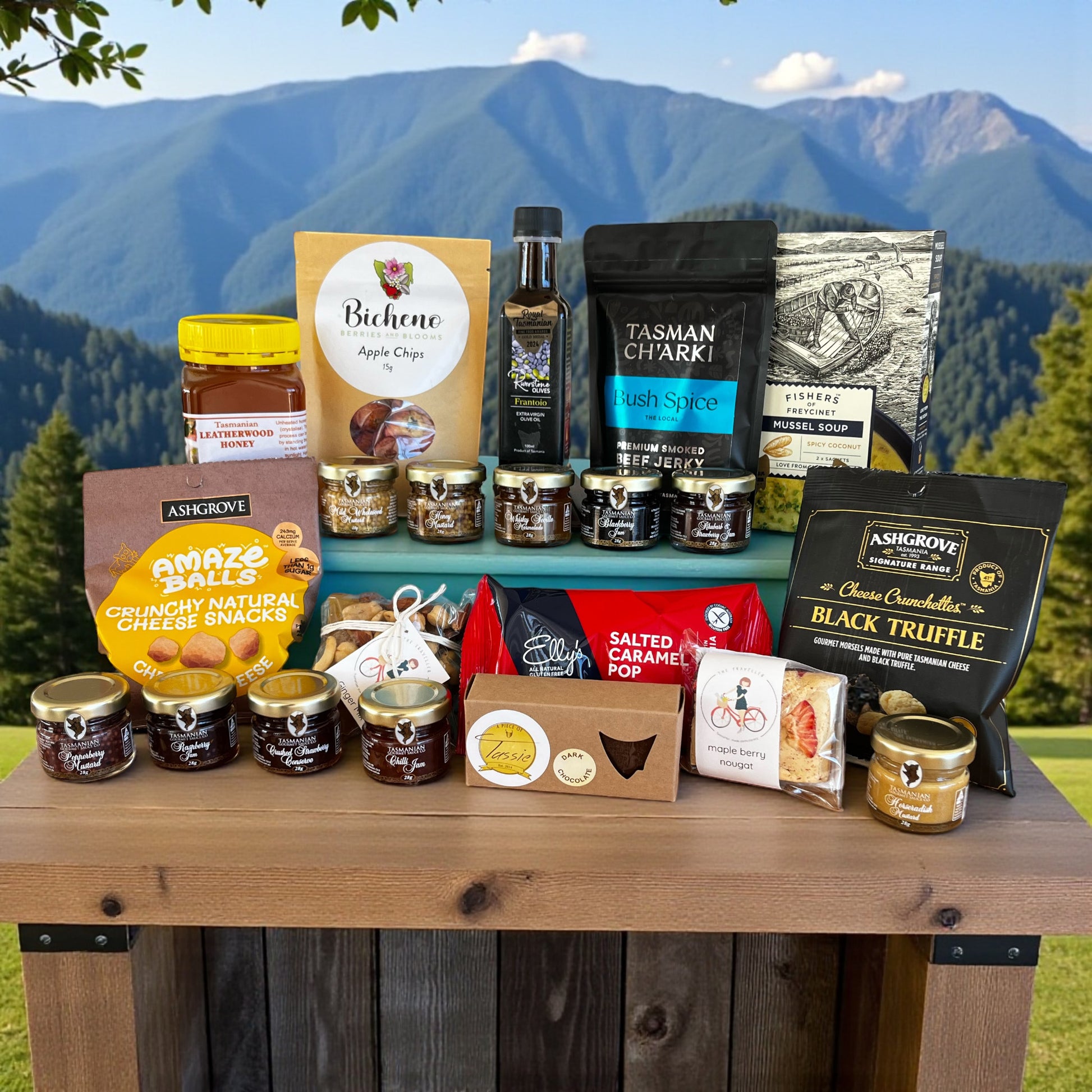 Assorted Tasmanian food products on a wooden table with mountains in the background