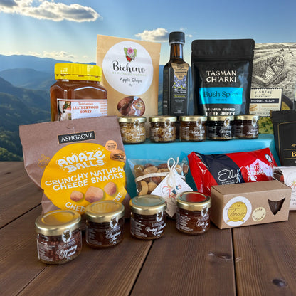 Assorted Tasmanian made food products on a wooden surface with a mountainous background.