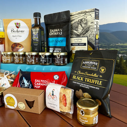 Assorted Tasmanian gourmet food products on a wooden table with a scenic background